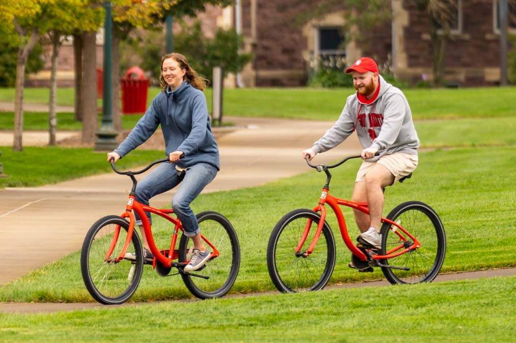 Two Students Riding Bikes on Campus