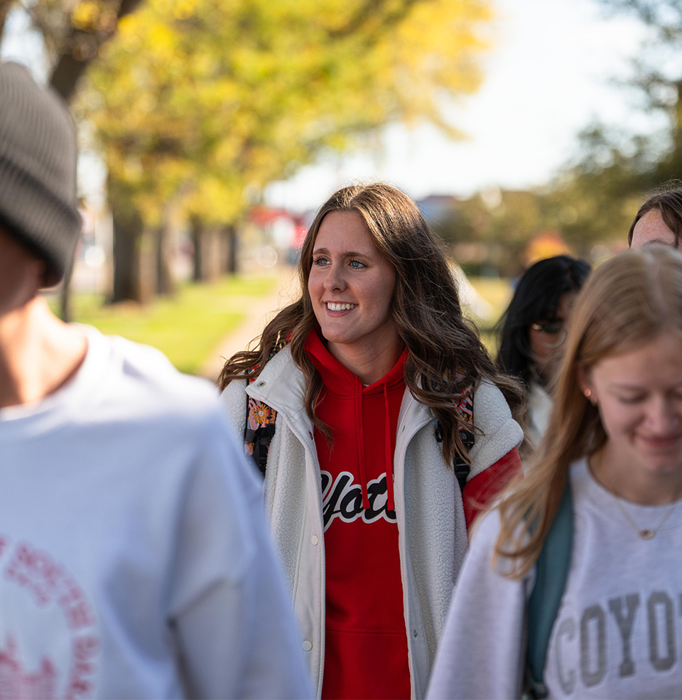 USD Student in a crowd of other smiling students looking off and smiling in the distance