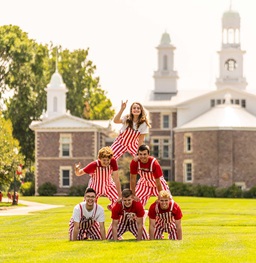The Crazies posing in a stunt pyramid while holding up Yote signs on the campus lawn.