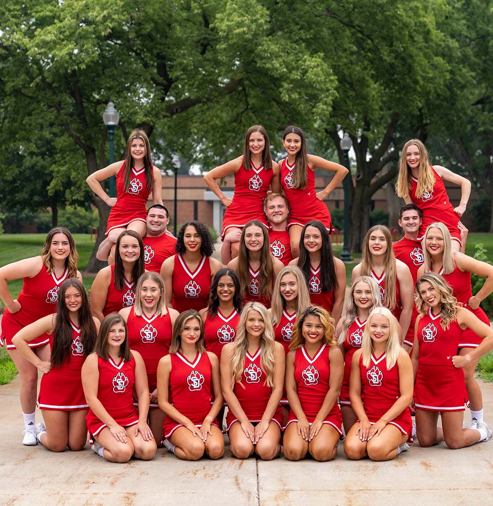 The USD Cheer team posing for a group picture on the center of campus.
