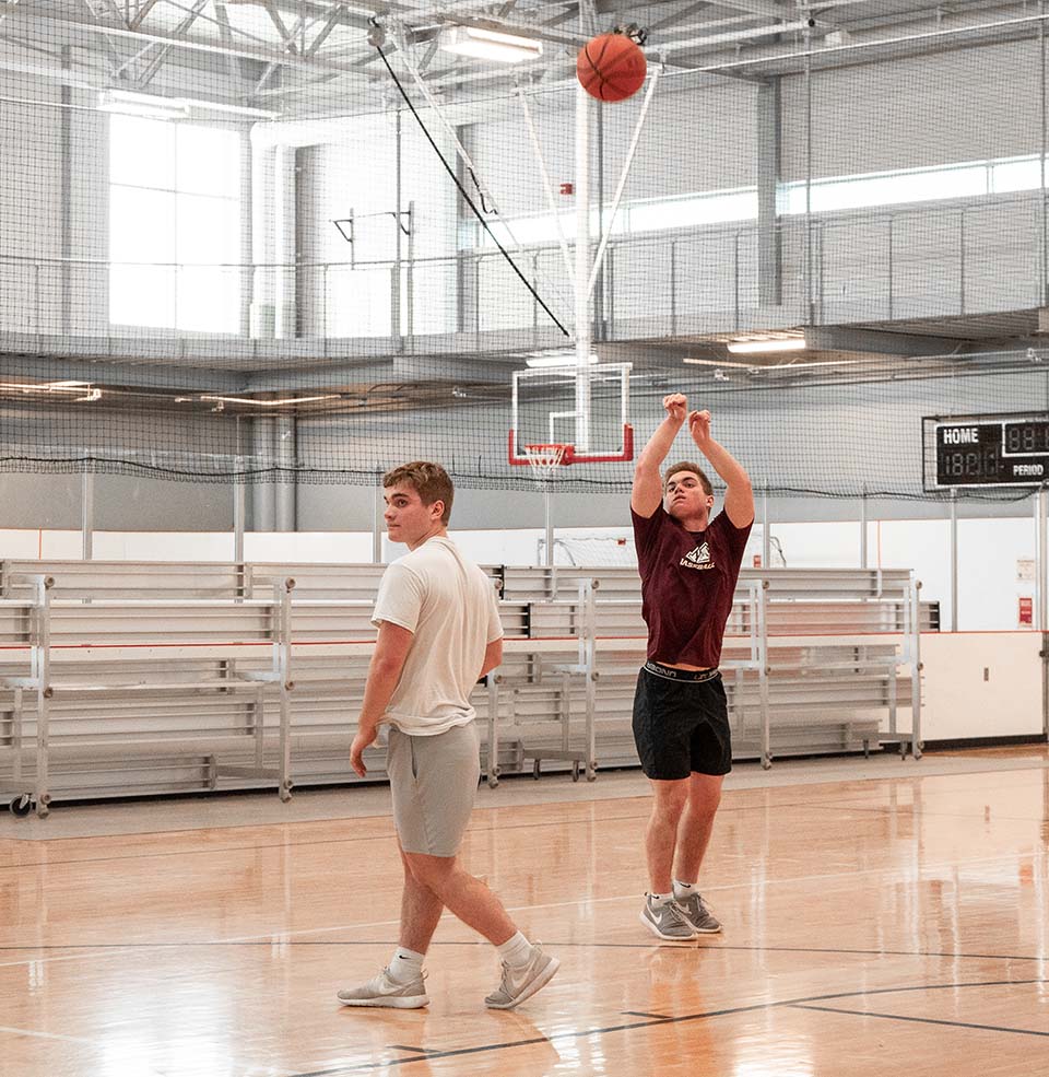 Two male students shooting a basketball on the Wellness Center court.