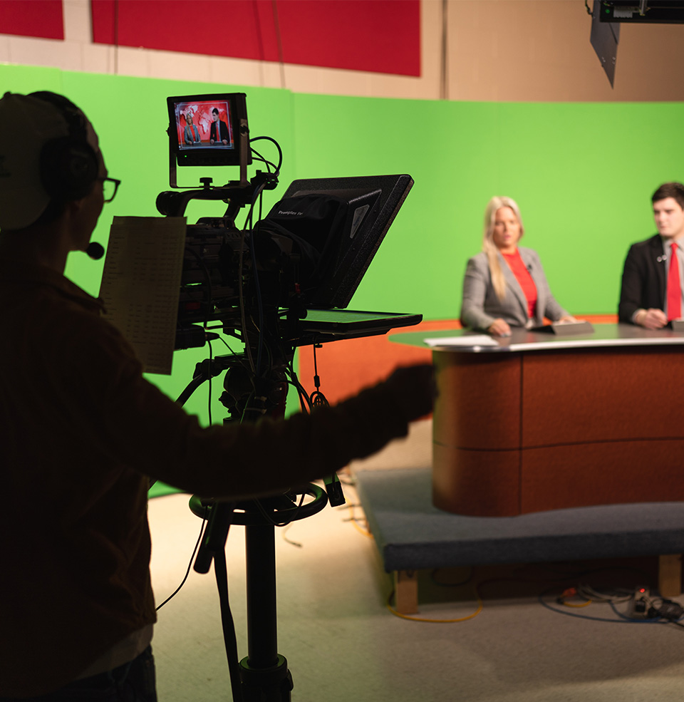 USD news cast photo behind the scenes with green screen and camera.
