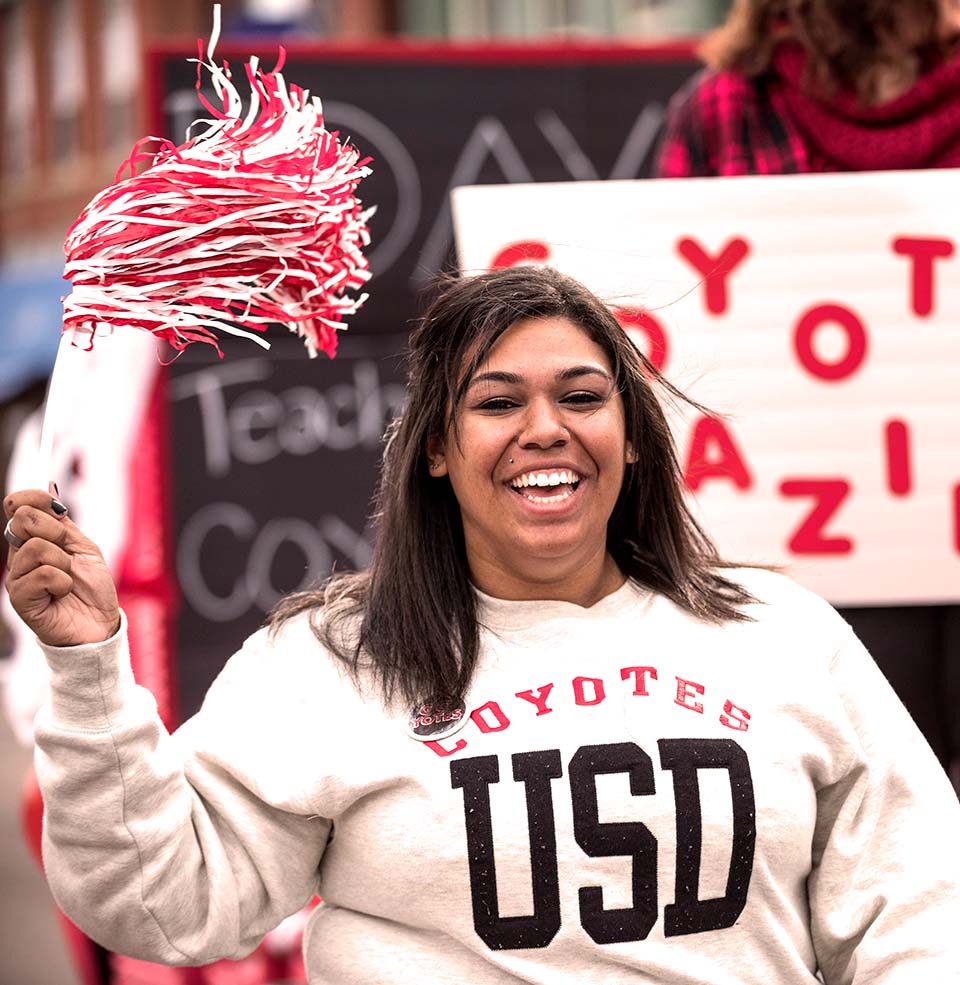  A USD Student marching in the D Days parade with a Crazies sign.
