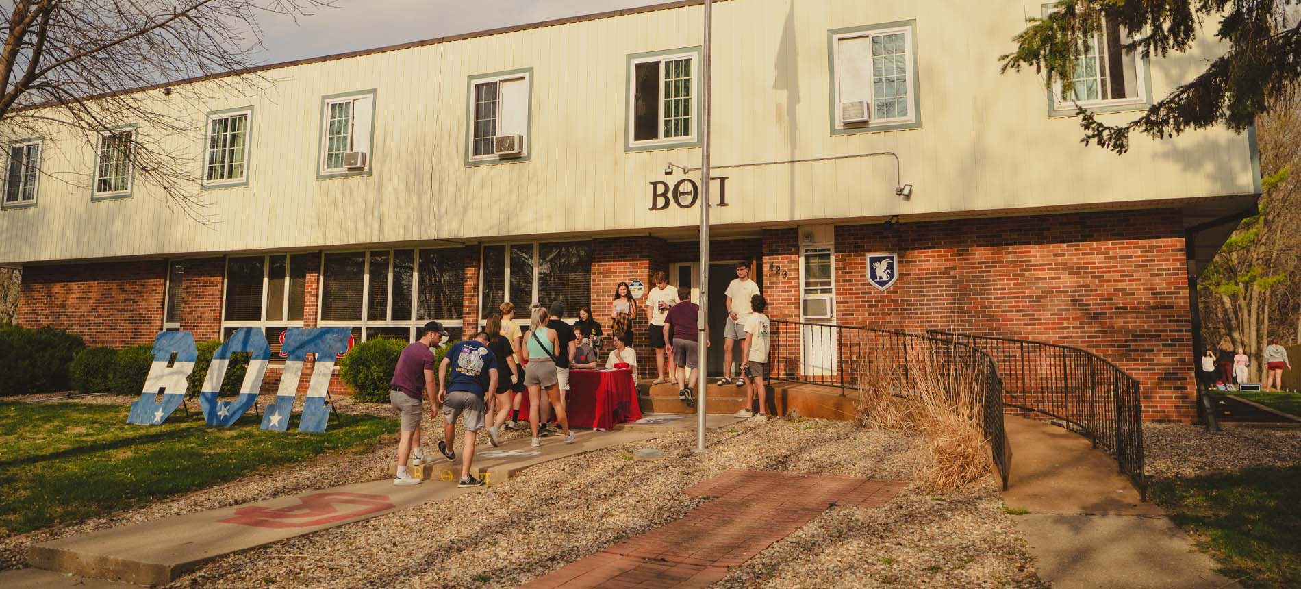 Fraternity students posing in front of their house.