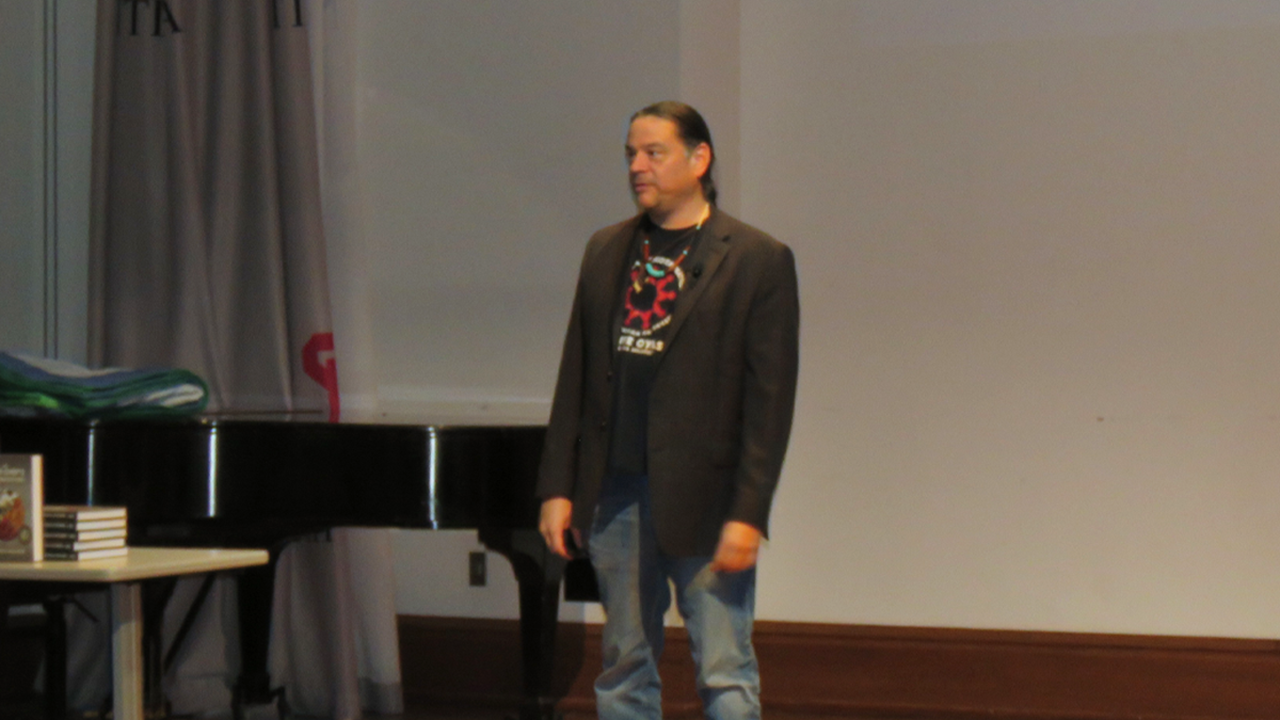 Sean Sherman stands on a stage and presents.
