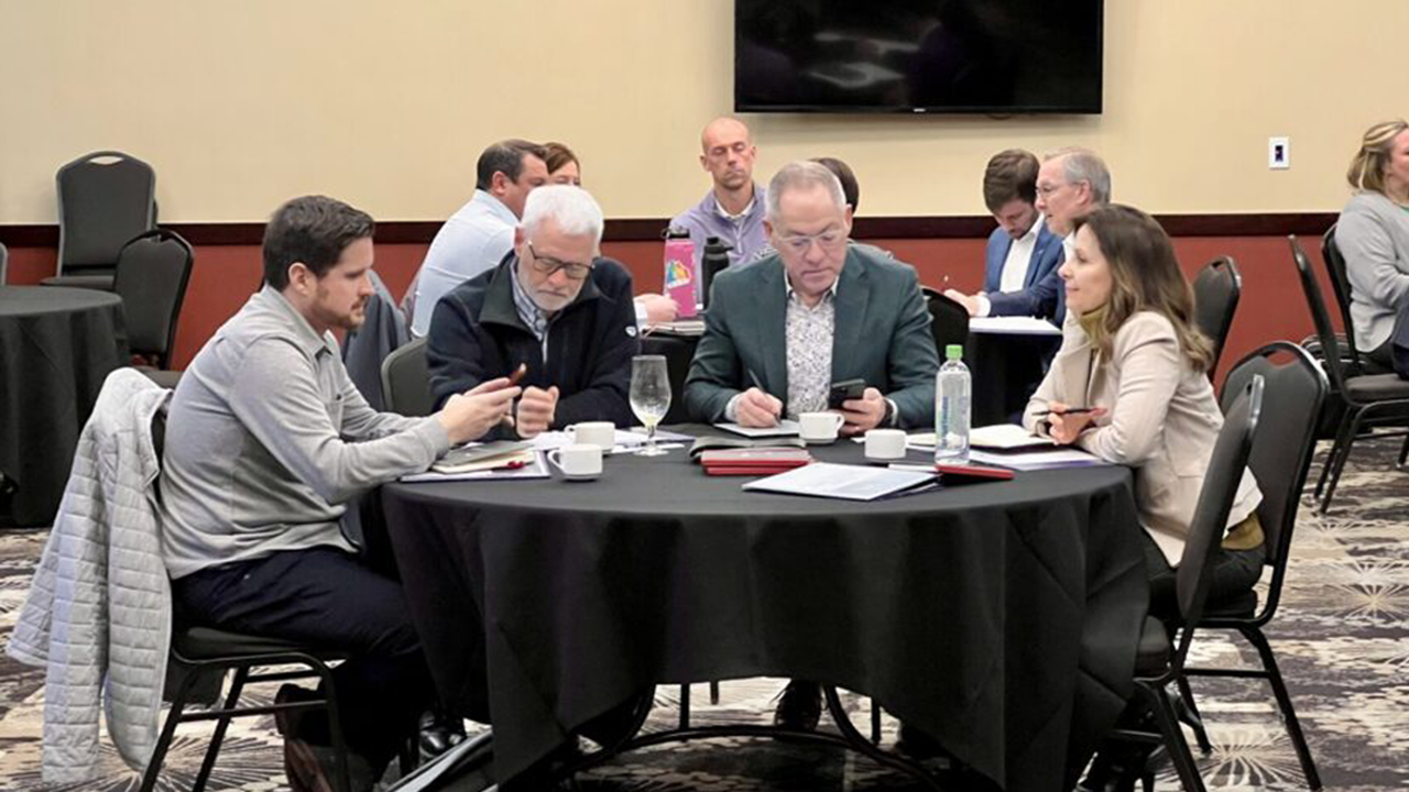 People sit around a table and look at papers at a conference.