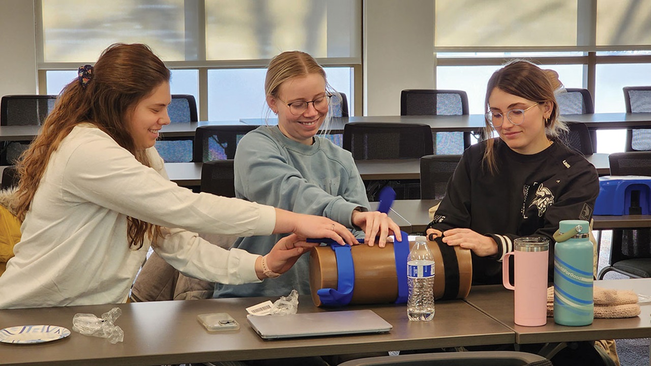Three transition to residency students working on medical device on table