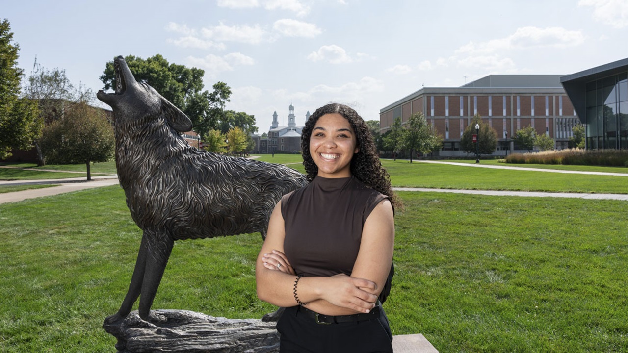 Olivia Allen stands near the Coyote Legacy Statue, with arms crossed, smiling at the camera. Olivia Allen stands near the Coyote Legacy Statue, with arms crossed, smiling at the camera.