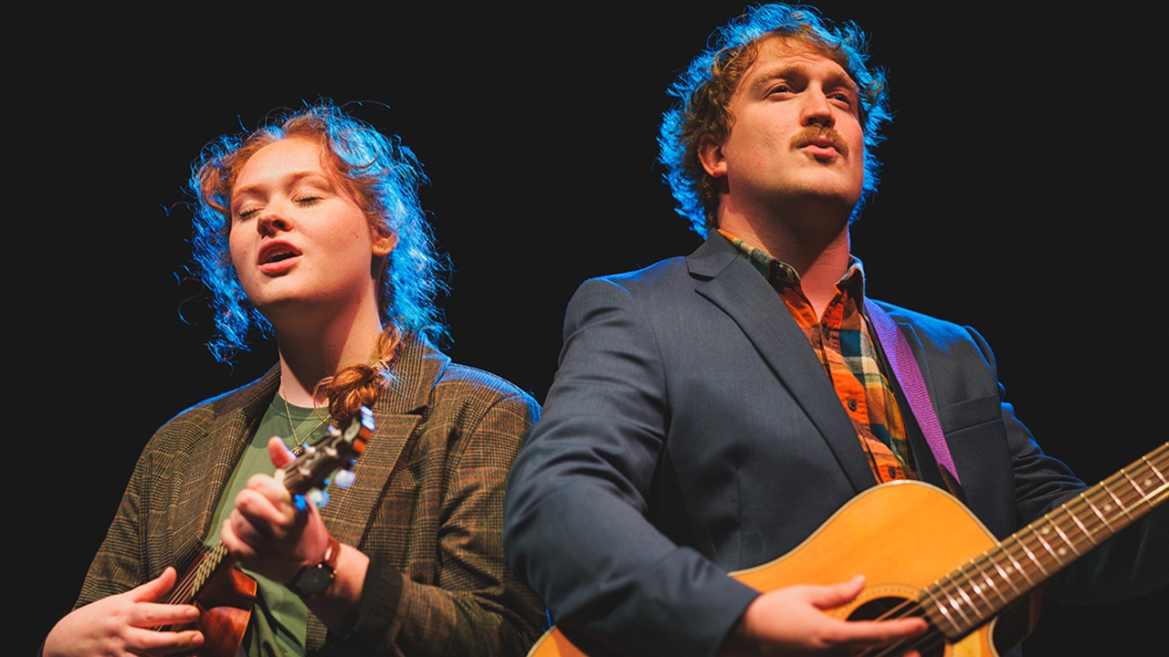 Two performers on stage playing instruments.