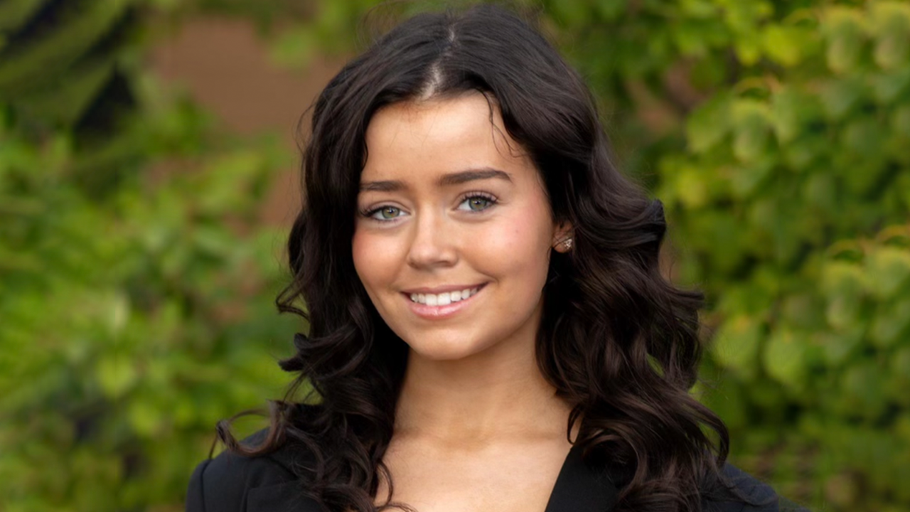 A headshot of Elisabeth Hart in front of green trees.