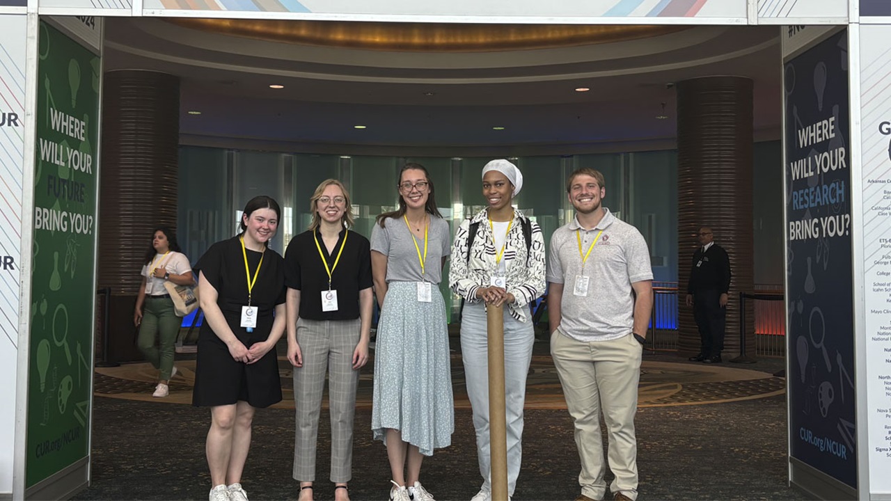 Five USD students at the NCUR Five USD students at the NCUR. They stand together in front of a doorway, smiling at the camera.