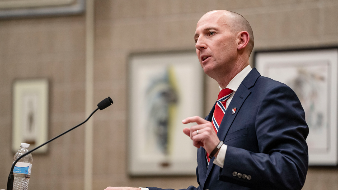 Dean Neil Fulton speaks passionately into a microphone at a stand in the law school courtroom.
