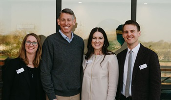 Members of the Prairie Family Business Association stand in front of glass doors, smiling at the camera.