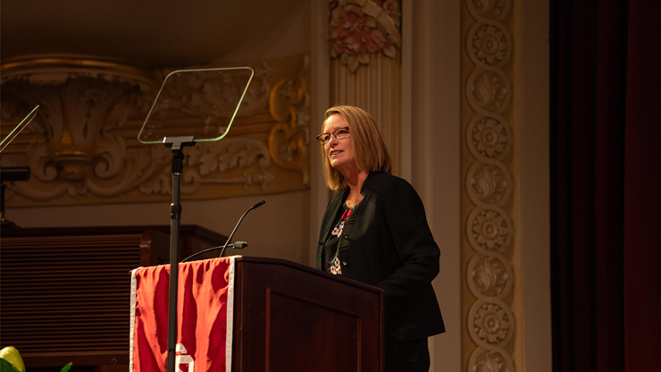 USD President Sheila K. Gestring stands in front of a podium, delivering the 2025 State of the University Address.