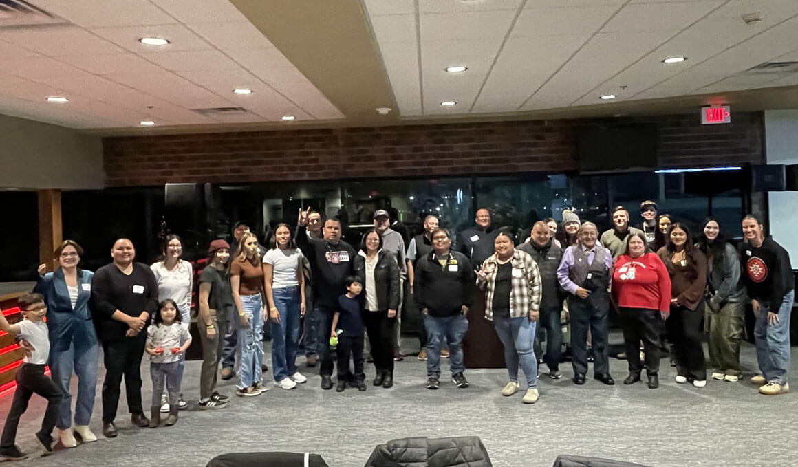 Attendees of the Lakota Education Conference pose for a group photo in a hotel or conference room. The group includes men and women of various ages, standing together after an event.