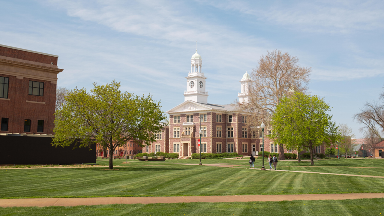 Old Main sits on the USD campus with students and faculty walking in front of it.