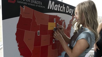 A USD Sanford School of Medicine student pins her photo to the map of the U.S. signifying where they were placed for residency. A USD Sanford School of Medicine student pins her photo to the map of the U.S. signifying where they were placed for residency.