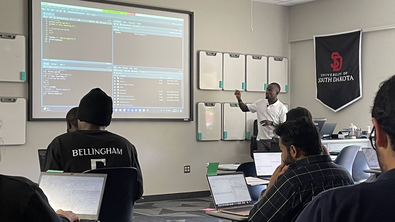 A professor teaches students on the subject of coding.