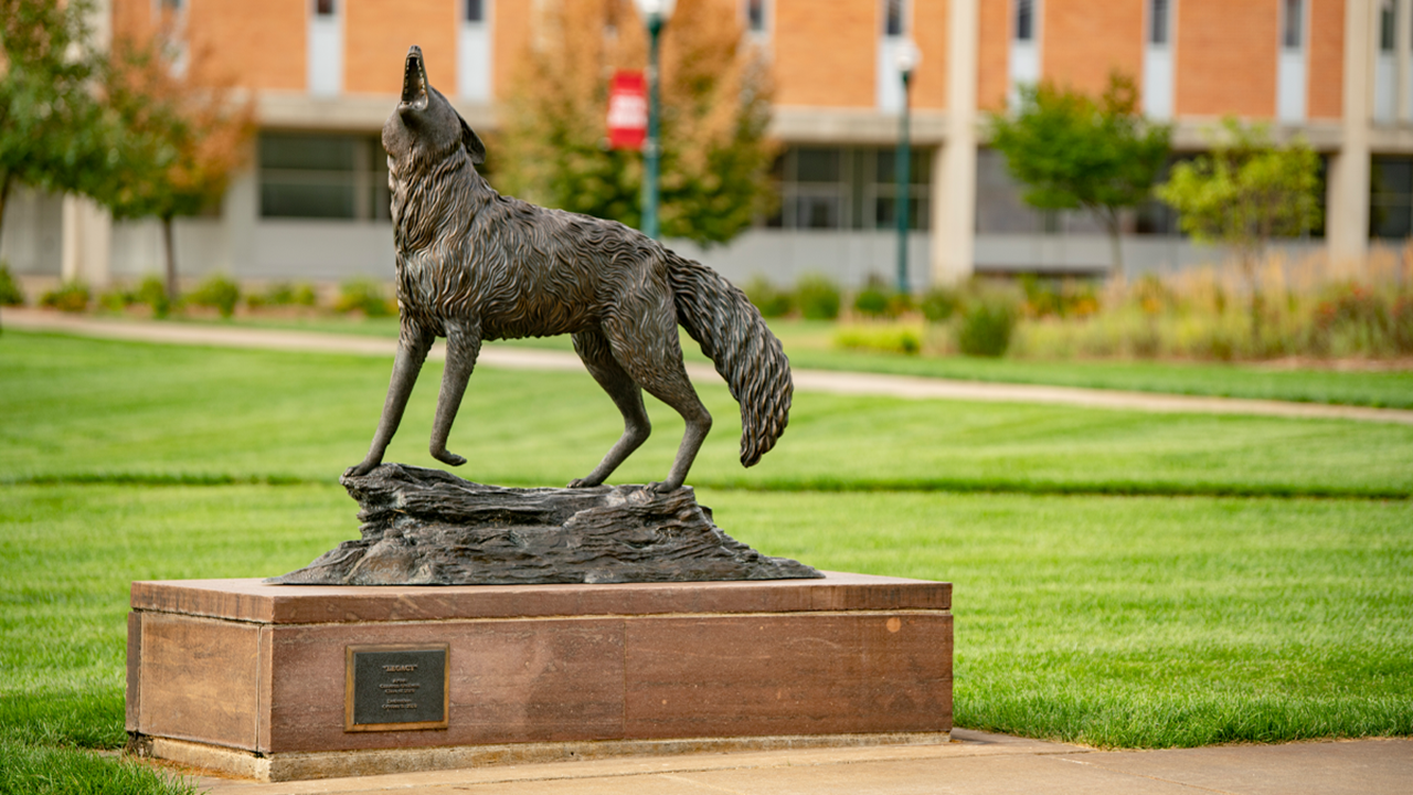 The USD Coyote Legacy statue sits on a bright green campus.