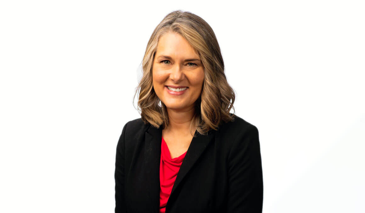 Darla Biel, Ed.D., sits and poses for her professional photo. She is wearing a black blazer with a red shirt and smiling at the camera.