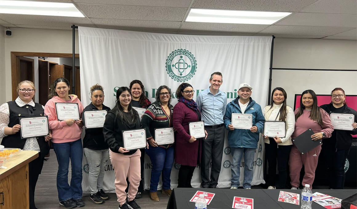 Personnel from USD – Sioux Falls and SDHCC members stand with their certificates in front of a backdrop that has the SDHCC logo on it.