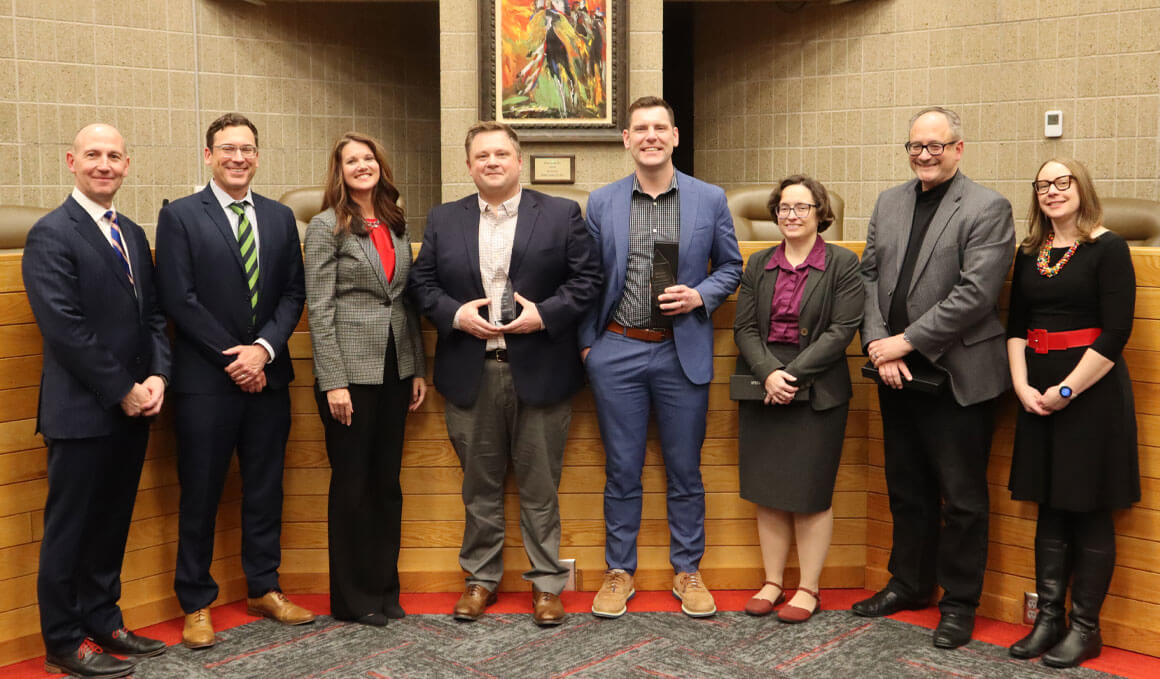 USD Knudson School of Law faculty members stand together in a conference room with Dean Neil Fulton, J.D. They are smiling at the camera.