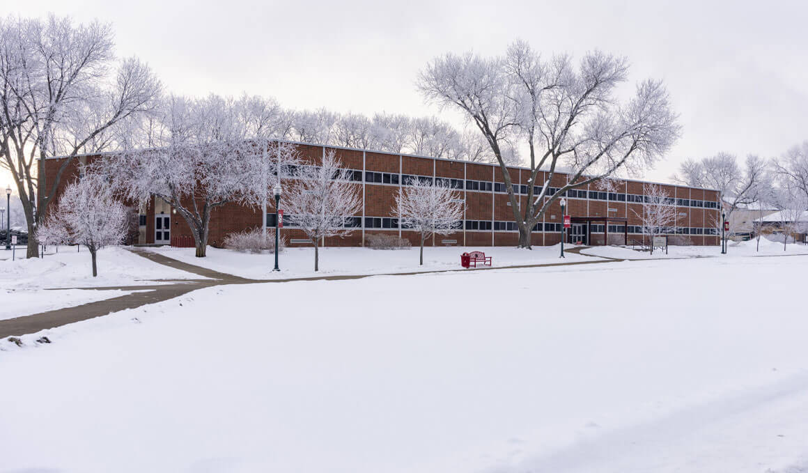 The Delzell Education Center sits on the USD campus, surrounded by snow-covered ground and frost-covered trees surrounding the brick building.