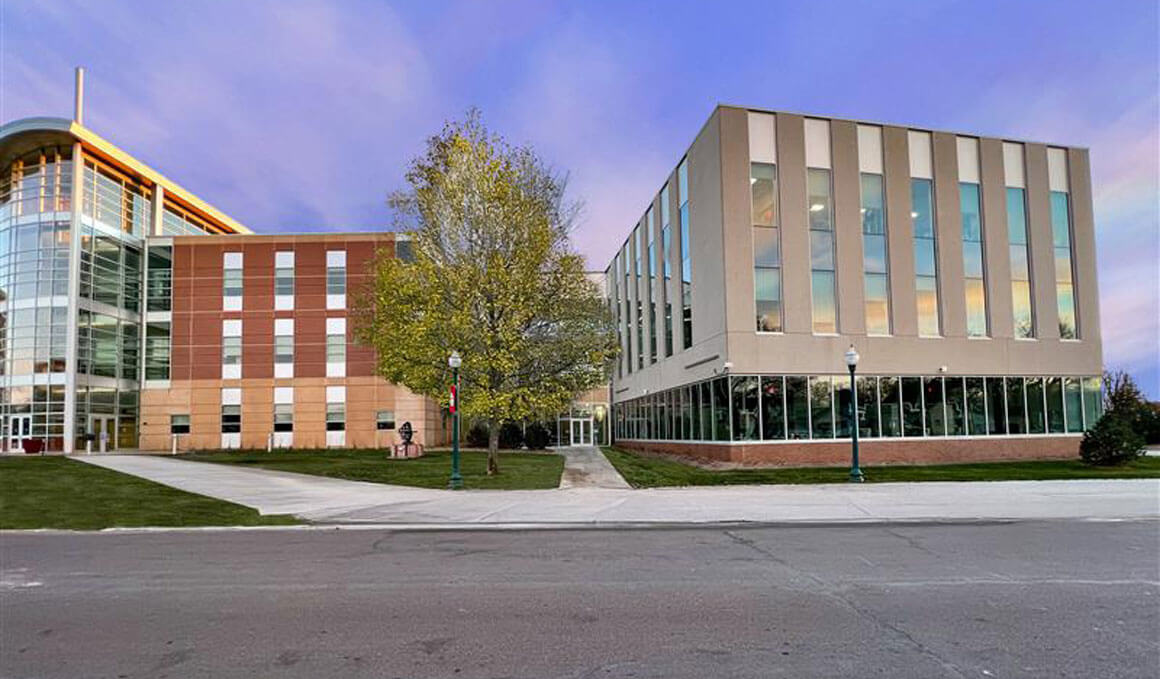 An exterior photo of USD's School of Health Sciences sits on the USD campus, with a blue sky illuminating the background.