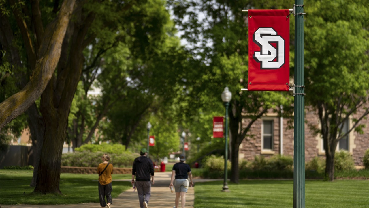 Three USD students walk together on the sidewalk's of USD's campus near Old Main. Three USD students walk together on the sidewalk's of USD's campus near Old Main.
