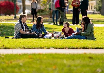 A group of students laying on the campus lawn and laughing.