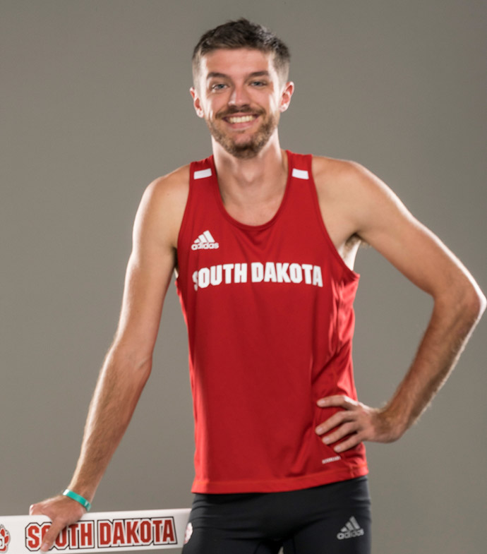 Success story Hugo Morvan leaning on a hurdle and smiling.