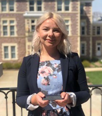 Success story Kate Solberg holding an award smiling.