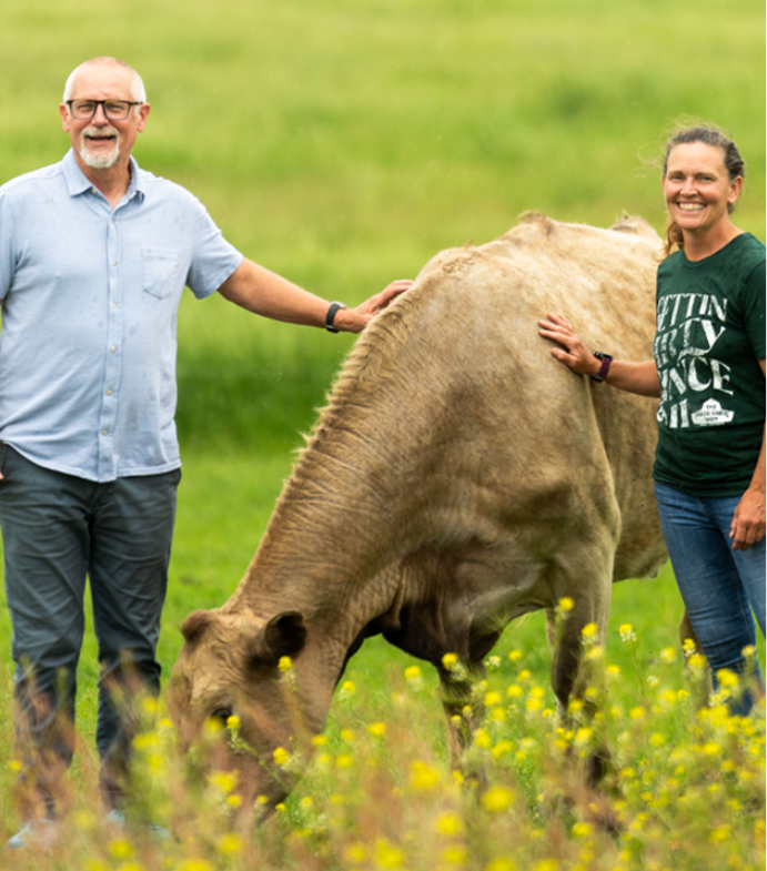 Nancy and Jeff Kiersten smiling in front of their cow.