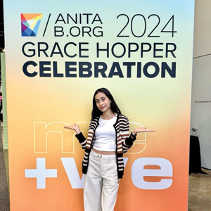 Bidya Bhattarai stands in front of a Grace Hopper Celebration sign.