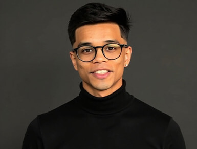 Shivansh Rastogi poses for the camera, smiling and wearing glasses and a black shirt.