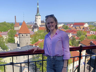 Elyse Whittemore in a European city, standing in front of buildings with steeples.