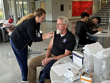 A man receives his flu vaccination in the atrium of the Beacom School of Business