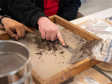 A USD student and faculty member sift through a collection of dirt in the new USD ARCHLAB.