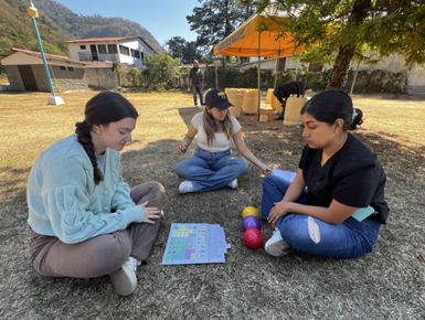 USD students sit with a Guatemalan student outdoors.