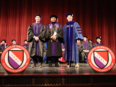 Rodney Axson stands on the stage during the hooding ceremony at the Knudson School of Law's graduation ceremony.