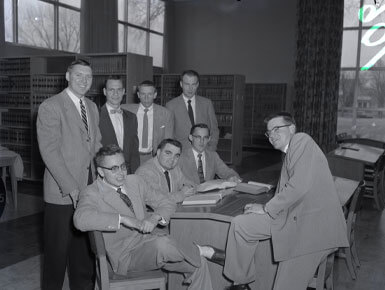 A historic, black and white photograph of Knudson School Law students who are grouped together and sitting in what appears to be a library.