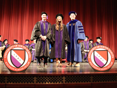 Alee Lewis stands on the stage during the hooding ceremony at the Knudson School of Law's graduation ceremony.