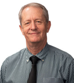 Dr. Tim Ridgway poses for his professional photo. He is wearing a blue, checkered shirt with a black tie.