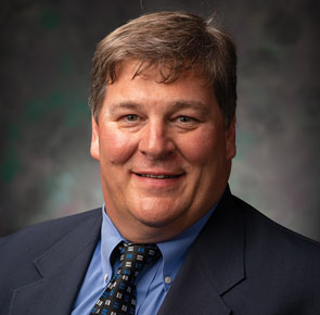 Eric Larson posing for headshot in front of gray wall