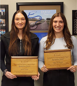 USD students Bailey Smith and Holly Gerberding pose for a picture with their plaques.