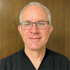 David Withrow posing for headshot in front of wooden wall