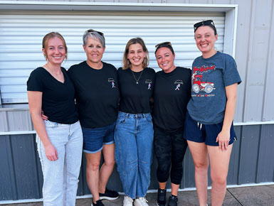 Rebecca Hofer, middle, stands with friends in front of an aluminum building during the "Walk to Remember" event for families experiencing pregnancy loss.