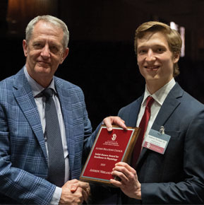 Andrew Nerland with Tim Ridgway smiling for photo while holding award and shaking hands