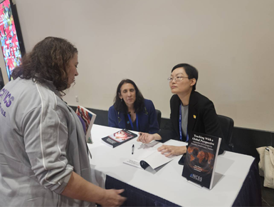 Jing Williams, Ph.D., associate professor of social studies education at USD signs a book for a fan.