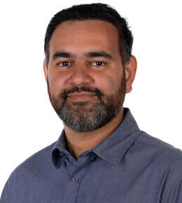 Anubhav Gupta poses for his professional photo. He is wearing a dark blue, button-up shirt.
